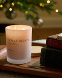 twelve nights candle lit on table near christmas tree