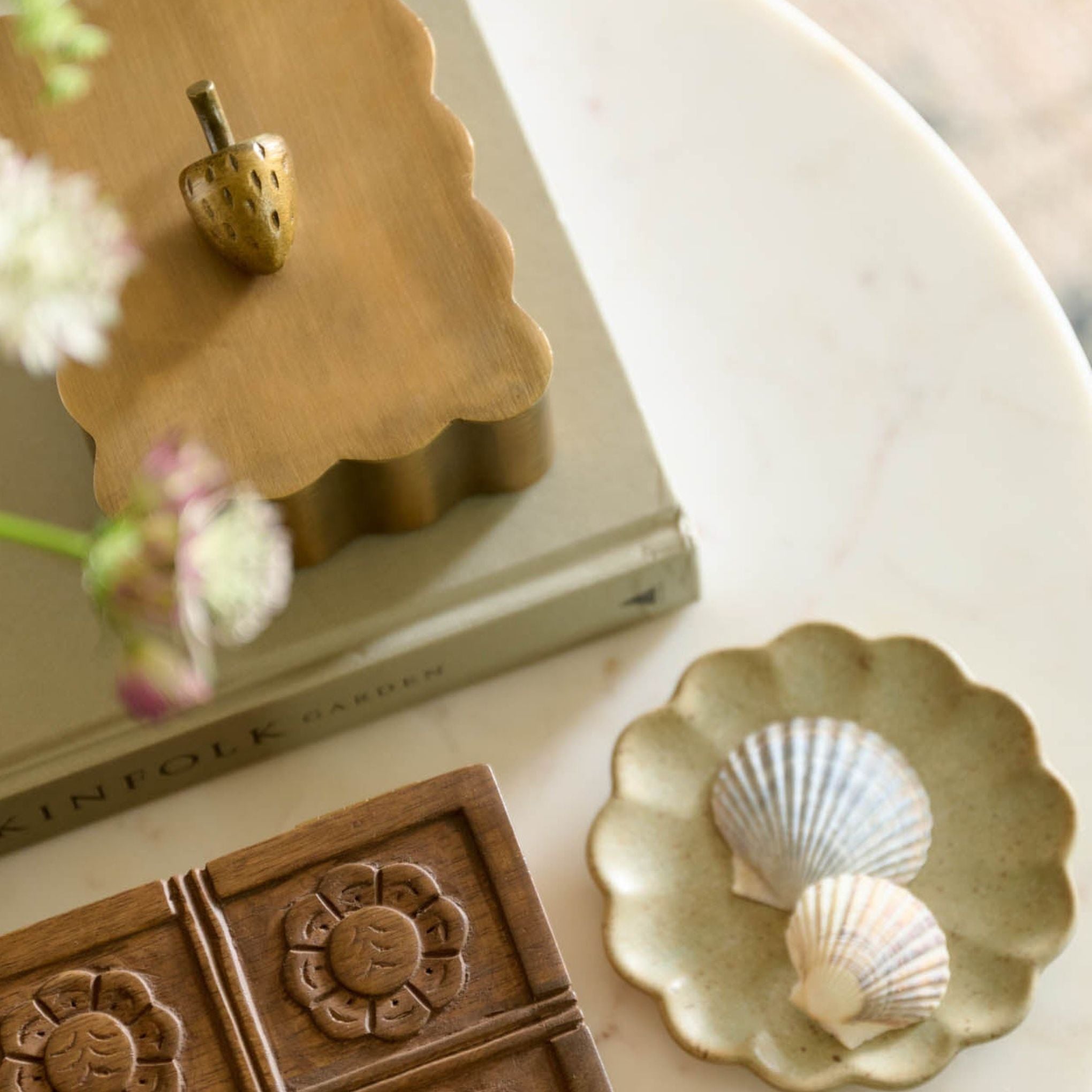 Decorative items including a wooden mold, ceramic dish with shells, and a book on a surface.