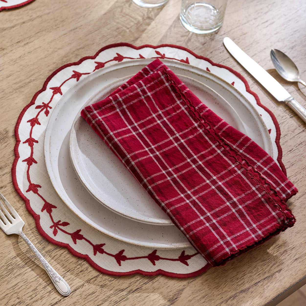 Plated dinner setting with red checkered napkin on a wooden table