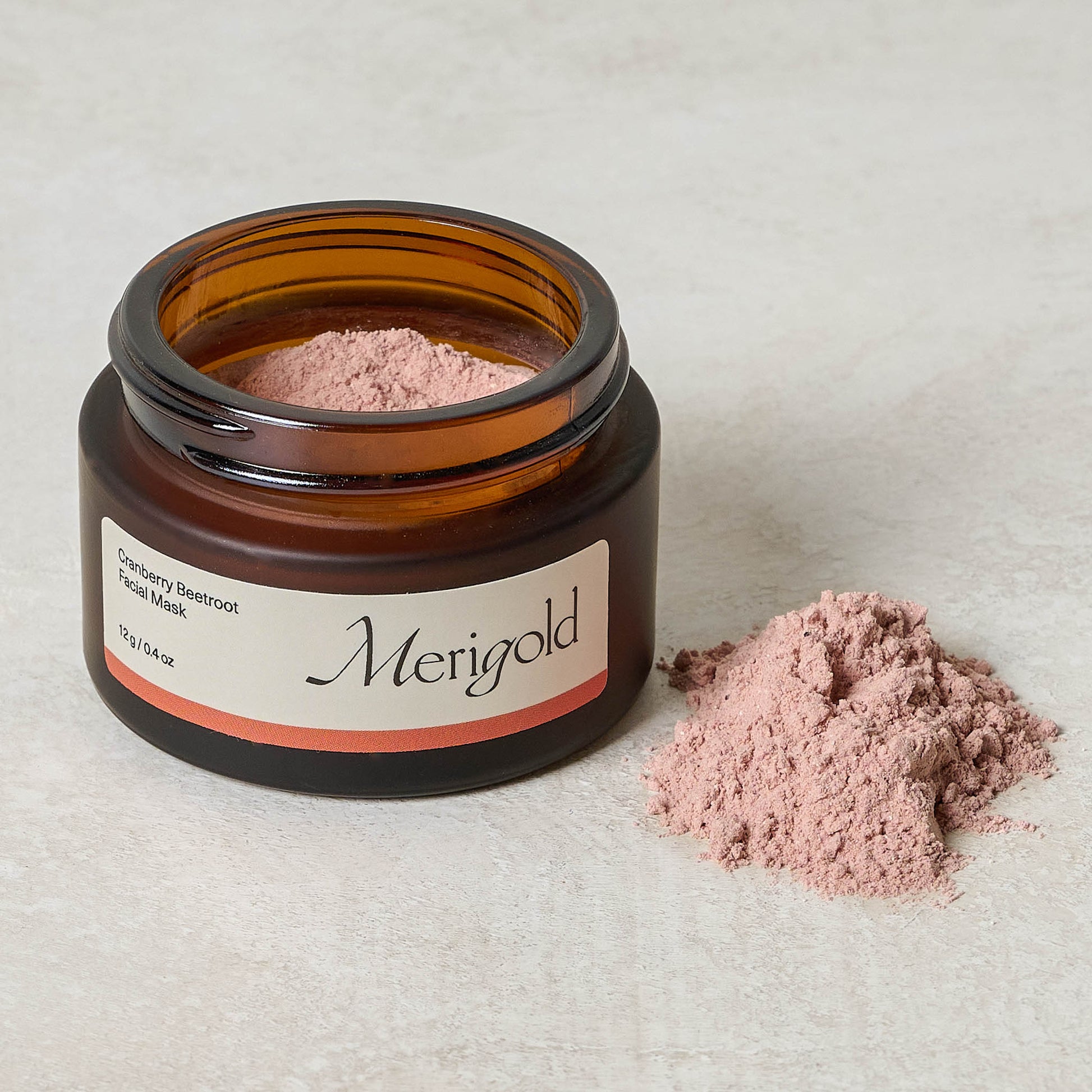 Merigold Cranberry Beetroot Facial Mask jar with top off next to a pile of powder