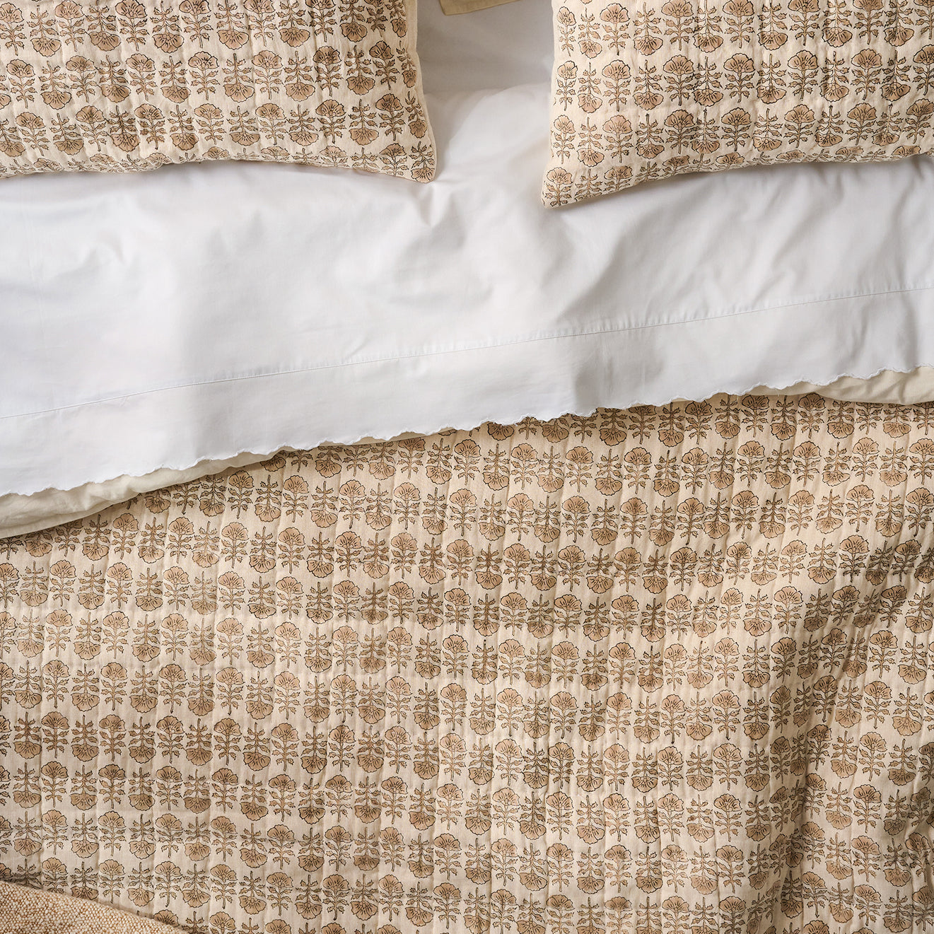 Flora Neutral patterned pillows and duvet cover on a bed.