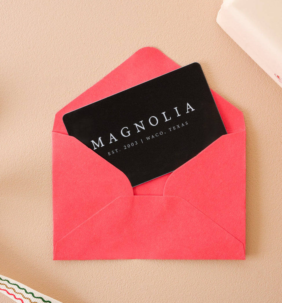 Black Magnolia gift card in a red envelope on a beige surface