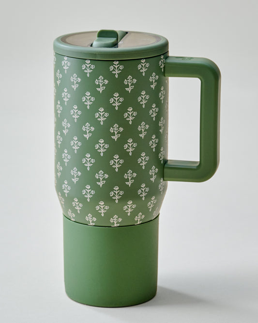 A green travel mug with a matching handle and lid, featuring a white repeating floral pattern on the upper half and a solid green lower half, set against a light gray background.
