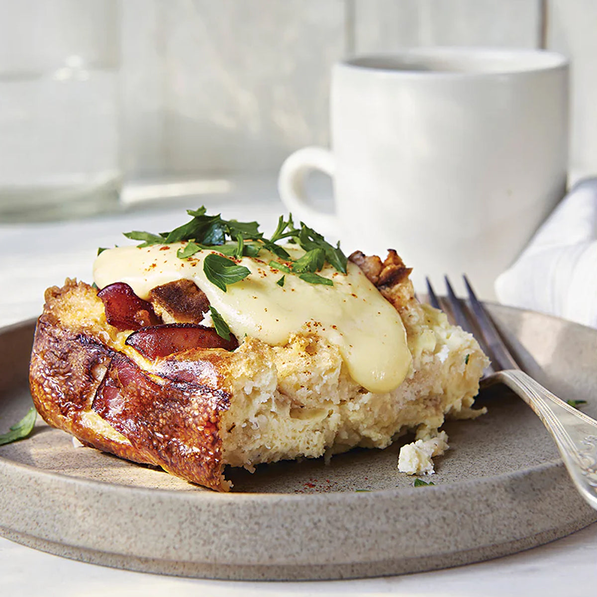 Dish with bread topped with cheese, bacon, and herbs on a plate with a fork.