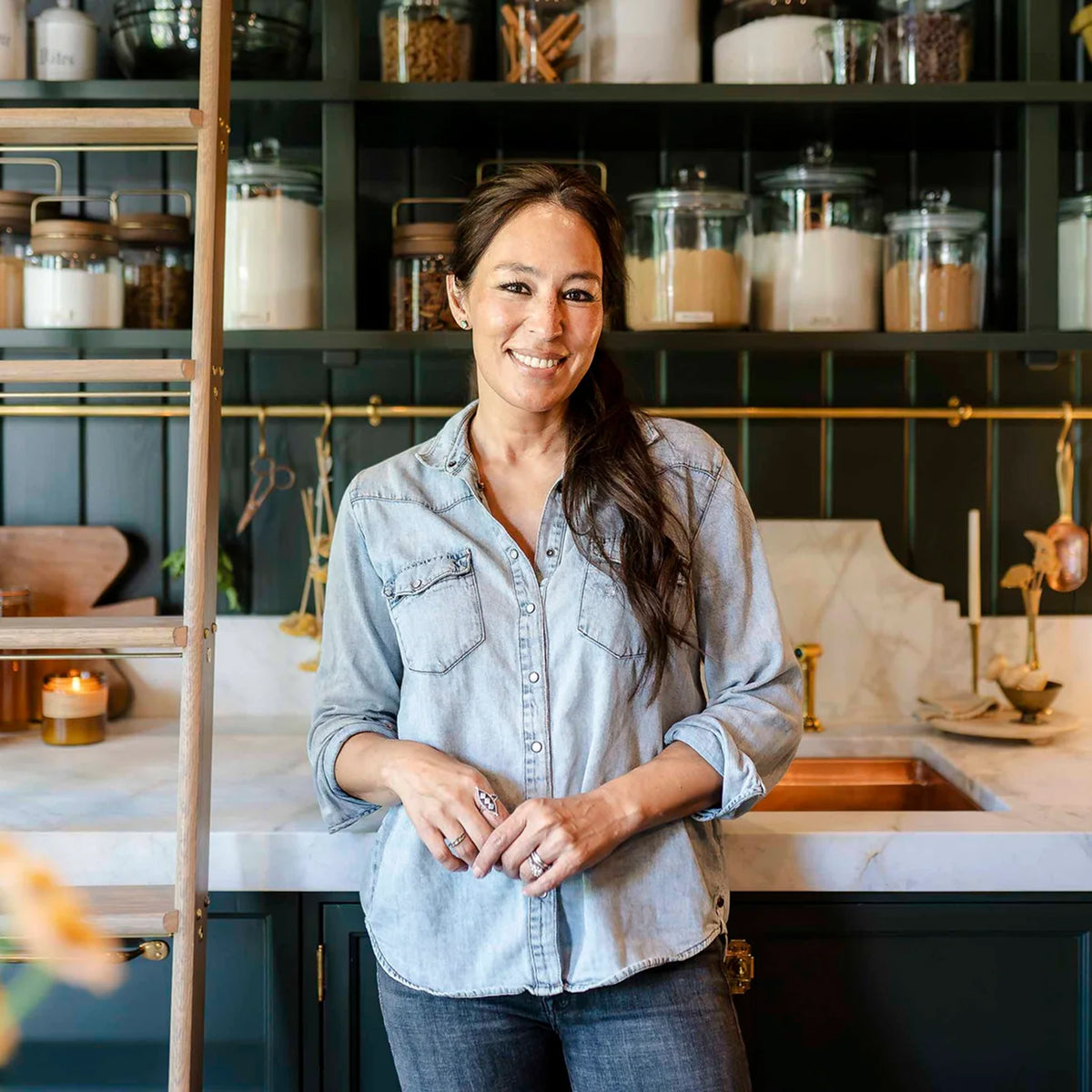 Joanna Gaines standing in her butler's pantry with shelves filled with canisters and a sink in the background.