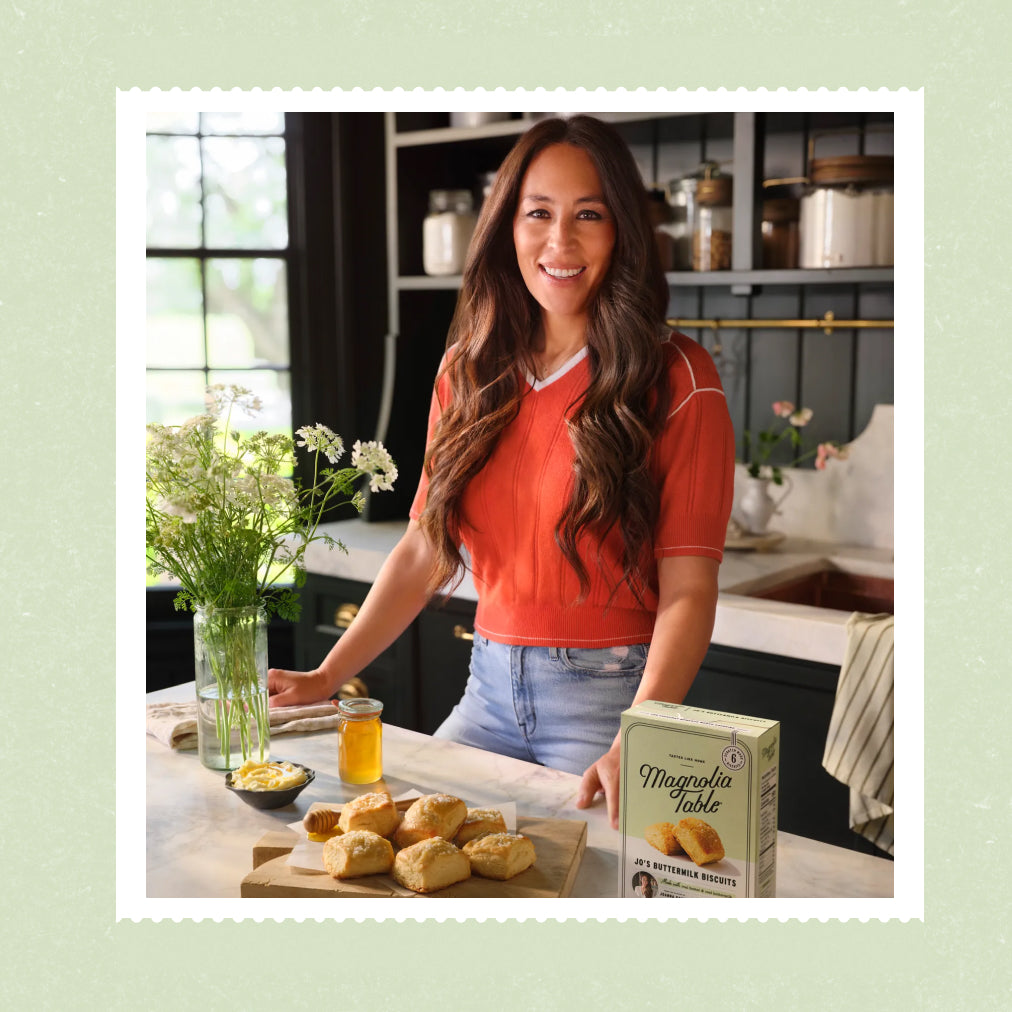 Joanna Gaines in her butler's pantry with a wood block full of jo's buttermilk biscuits and a box of her frozen buttermilk biscuits.