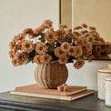 Sienna Mum Bouquet shown in rattan vase styled on dresser