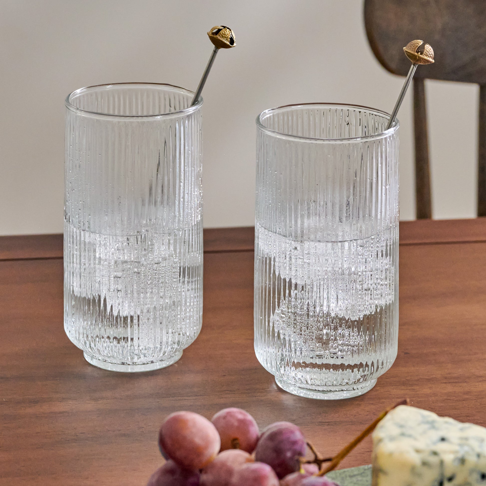 Brass Jingle Bell Cocktail Stirrers shown in glasses of water