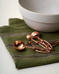 Hammered Copper Measuring Spoons on top of tea towel