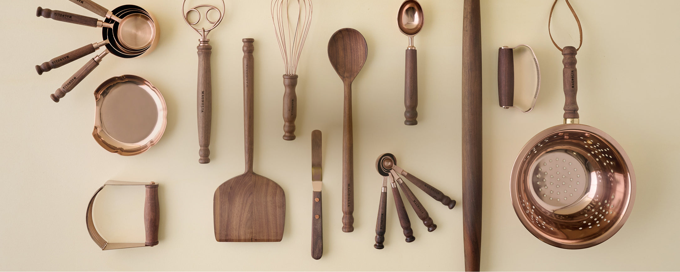 Collection of copper and wooden kitchen utensils on a beige background