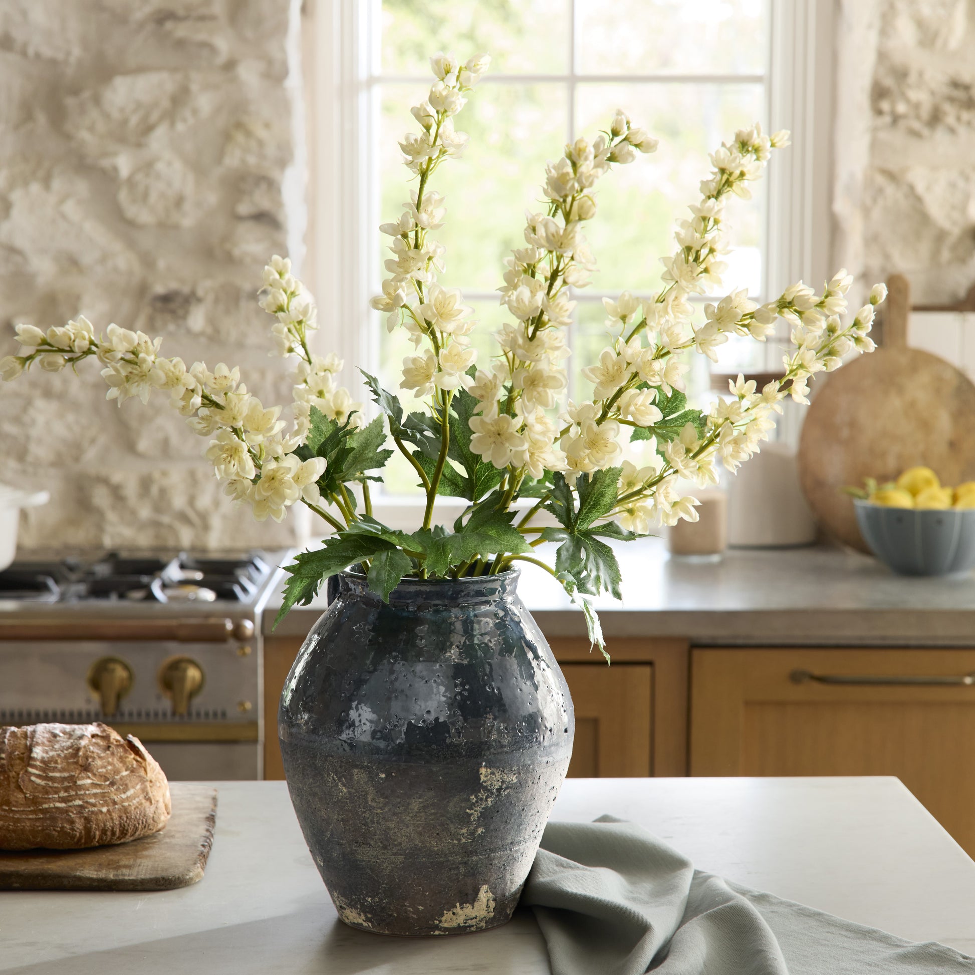 Decorative vase with cream larkspur flowers on a kitchen counter