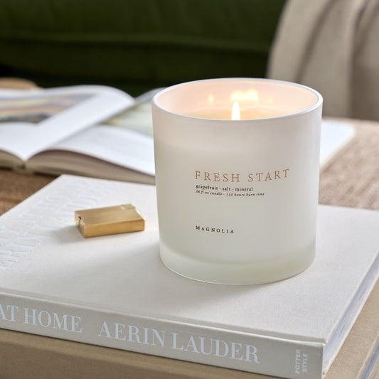 magnolia fresh start candle on stacked books