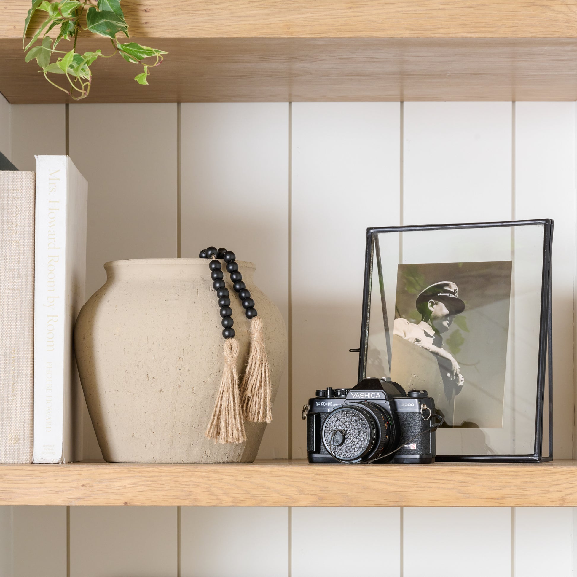 small textured adrienne vase on shelf next to a camera and a framed photo