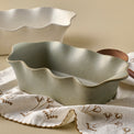 Loden Green Scalloped Loaf Pan shown with tea towel and serveware