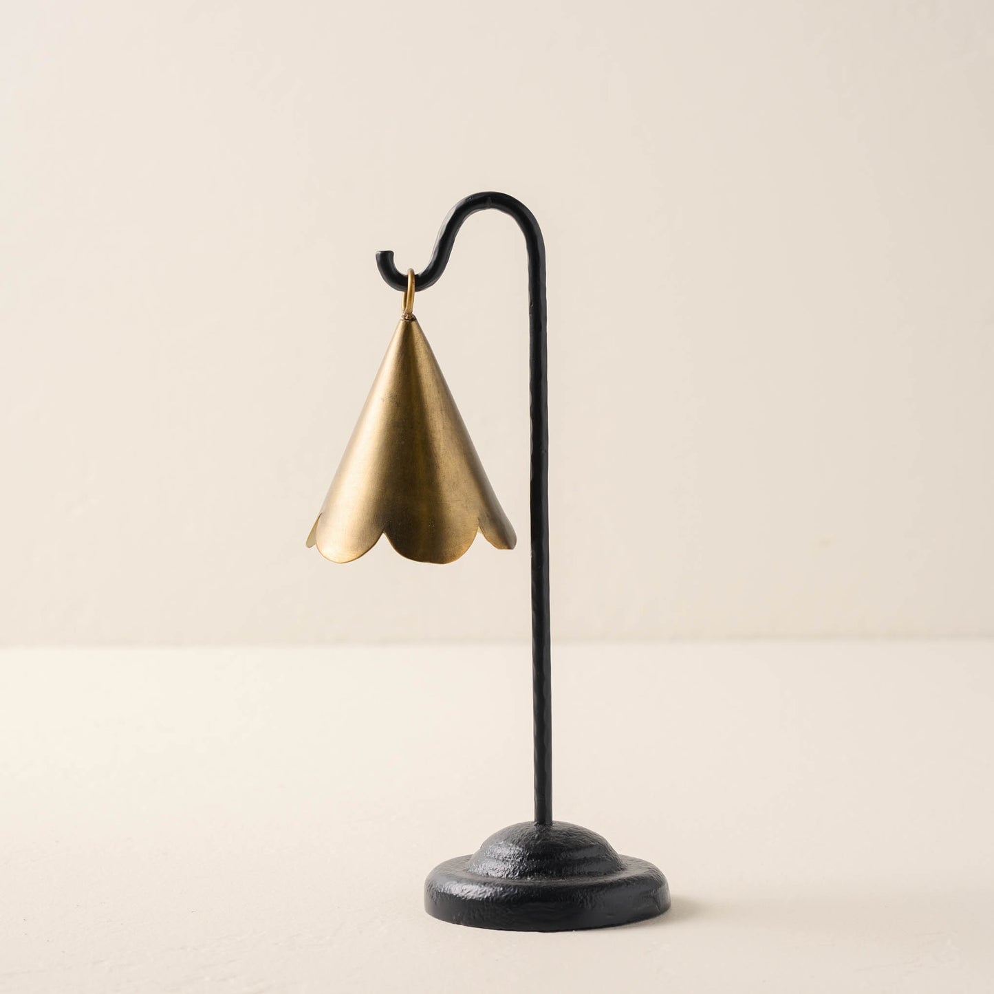 small sized brass scallop bell hanging from black metal stand