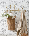 Woven Scalloped Wall Basket hanging on brass wall hook with faux floral stems