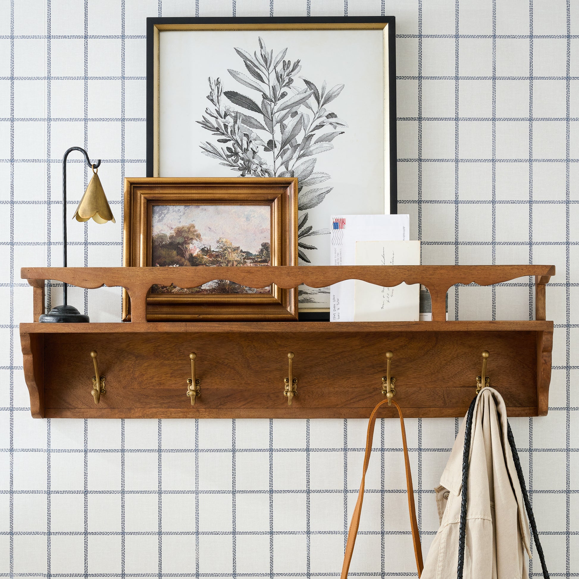 Daphne Wood and Brass Display Shelf on a wall with framed art on top