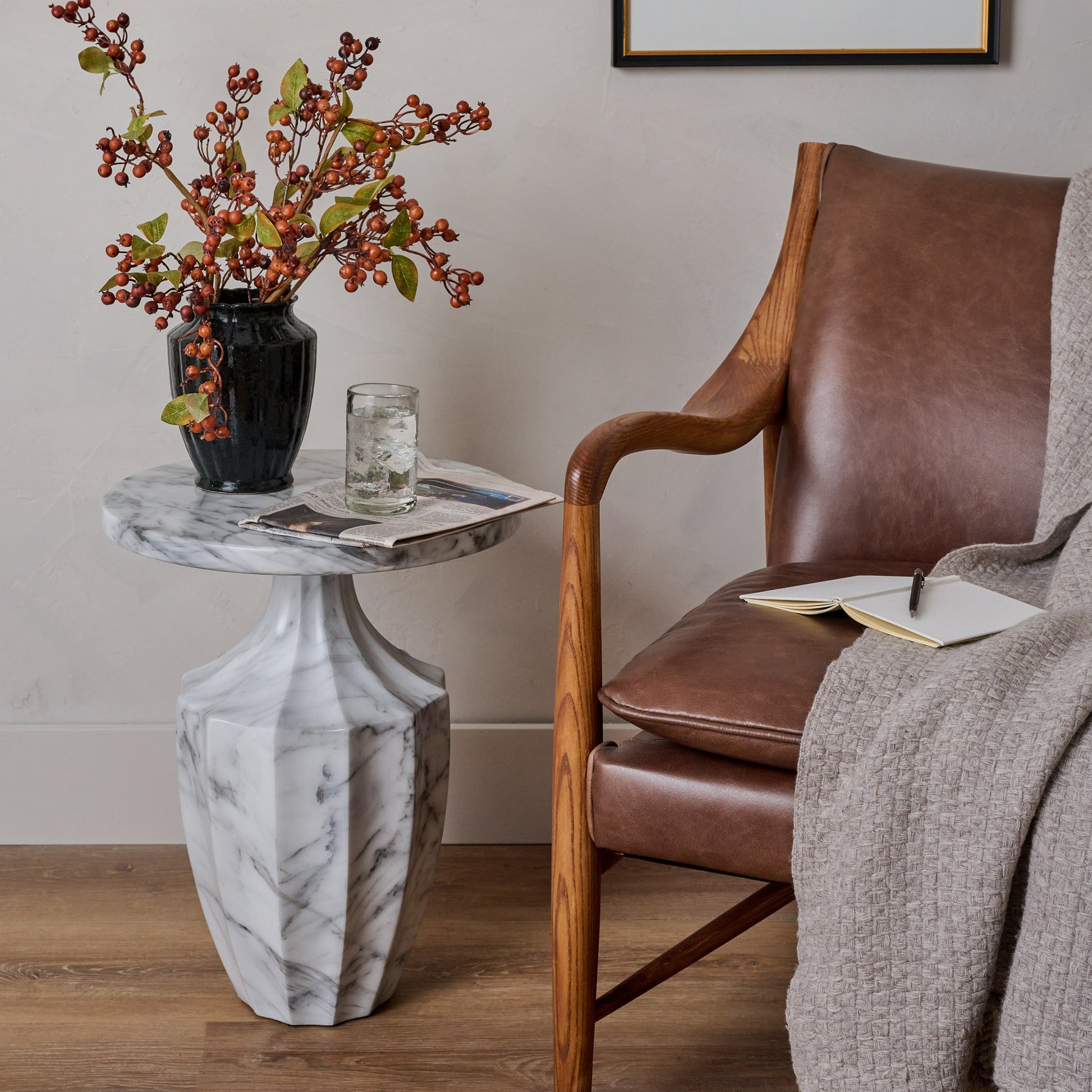 Fluted End Table shown holding vase of flowers and glass of water next to chair