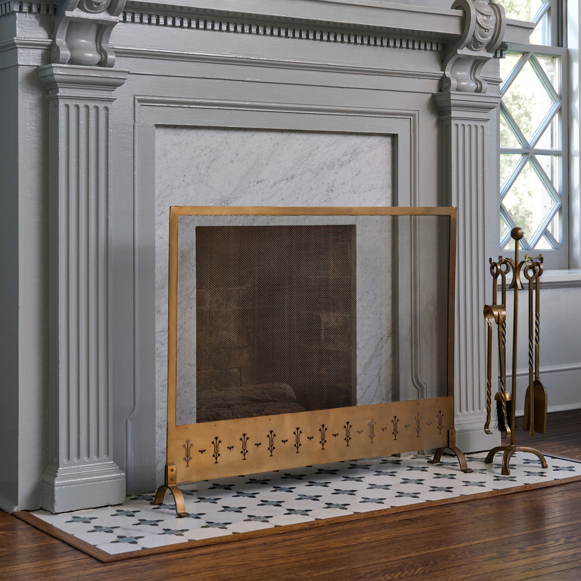 Antiqued Brass Tulip Carved Fireplace Screen shown by fireplace