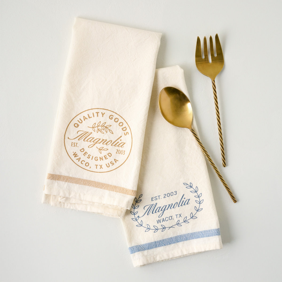 Magnolia Est. Blue Tea Towel shown with serving utensils and another tea towel
