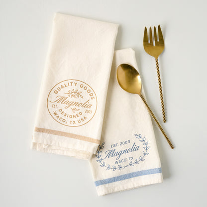Magnolia Est. Blue Tea Towel shown with serving utensils and another tea towel