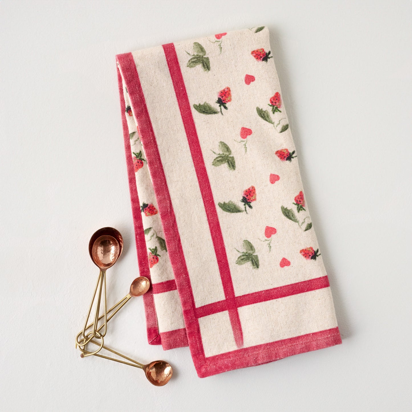 Magnolia Strawberry + Hearts Tea Towel  shown with measuring spoons