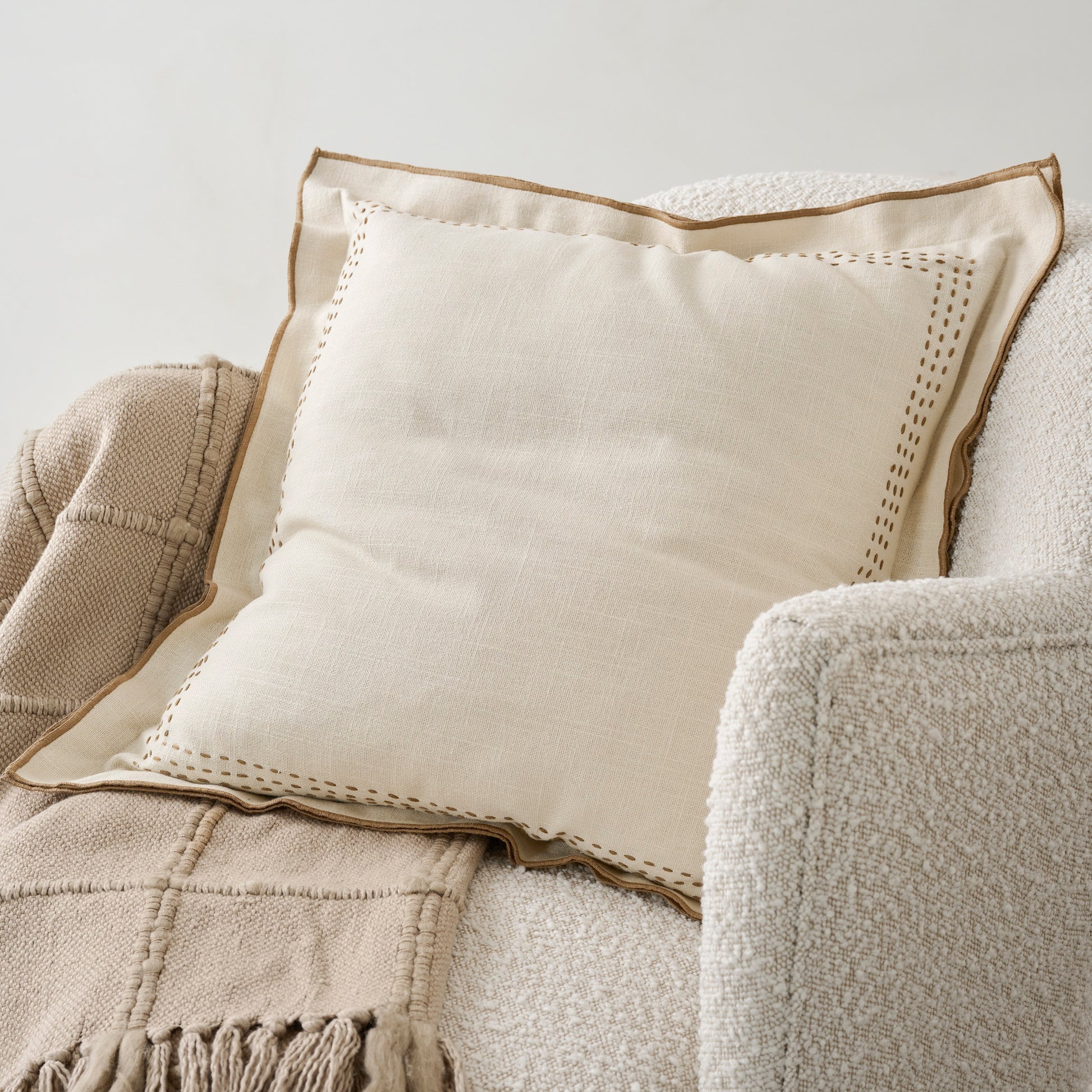 Oatmeal Felix Embroidered Pillow on chair