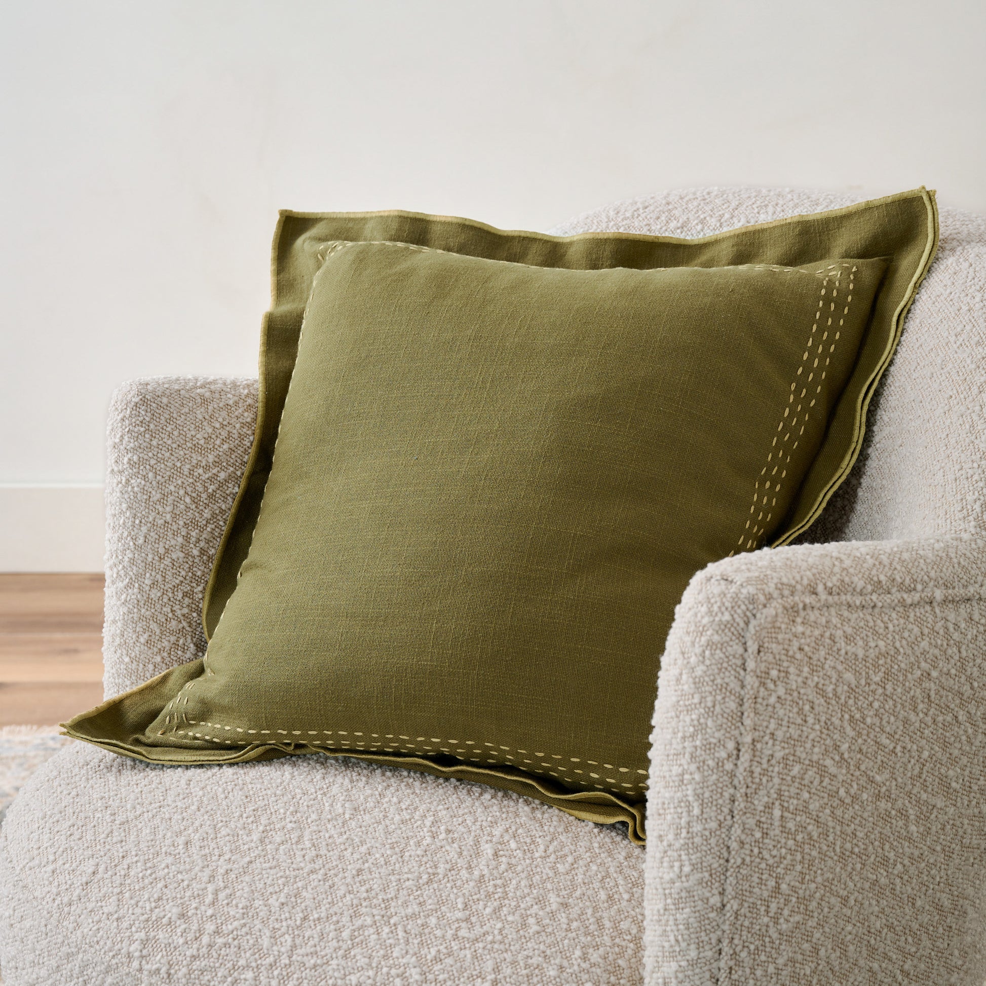 Nutria Felix Embroidered Pillow on chair