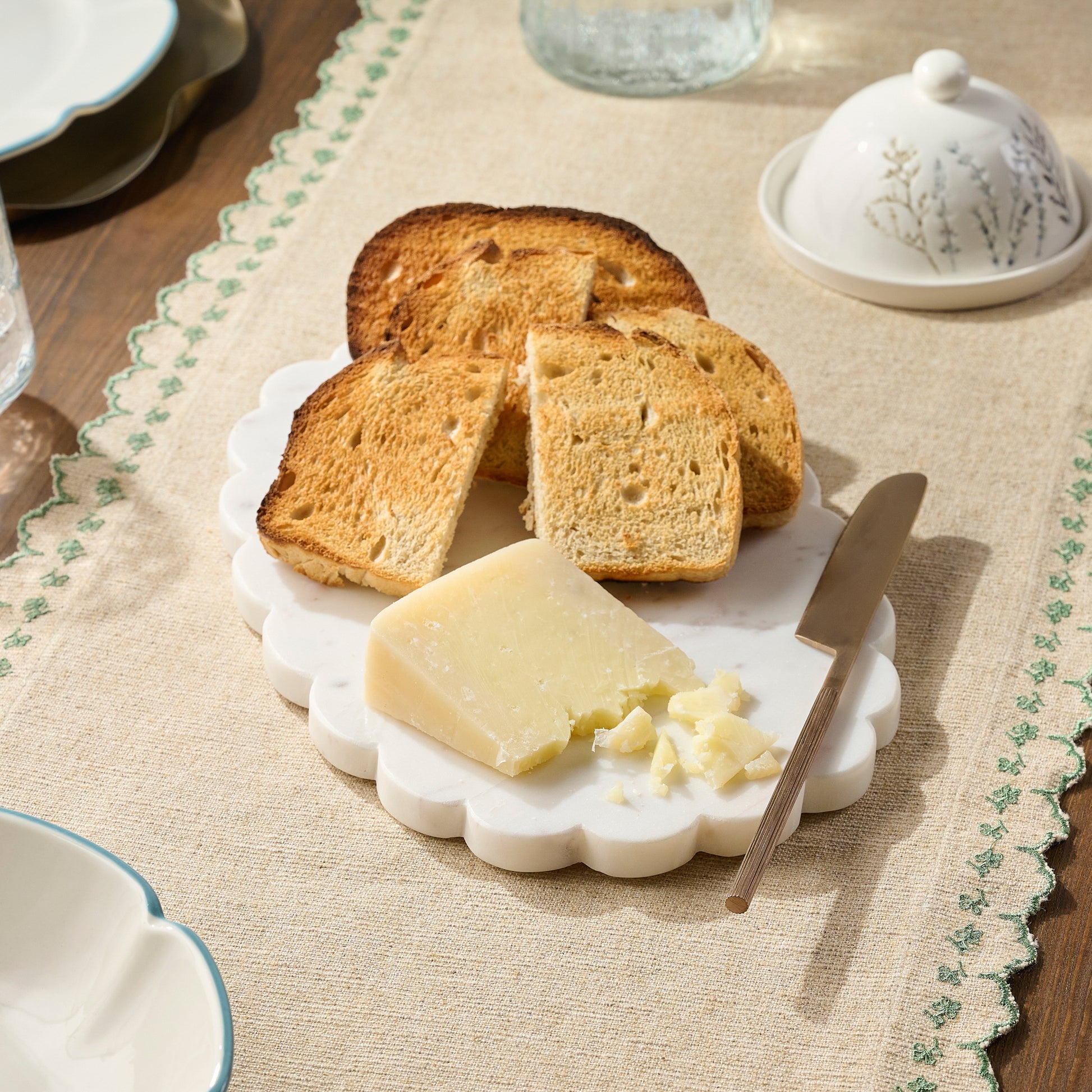 White Marble Scalloped Serving Board shown on table with bread and cheese