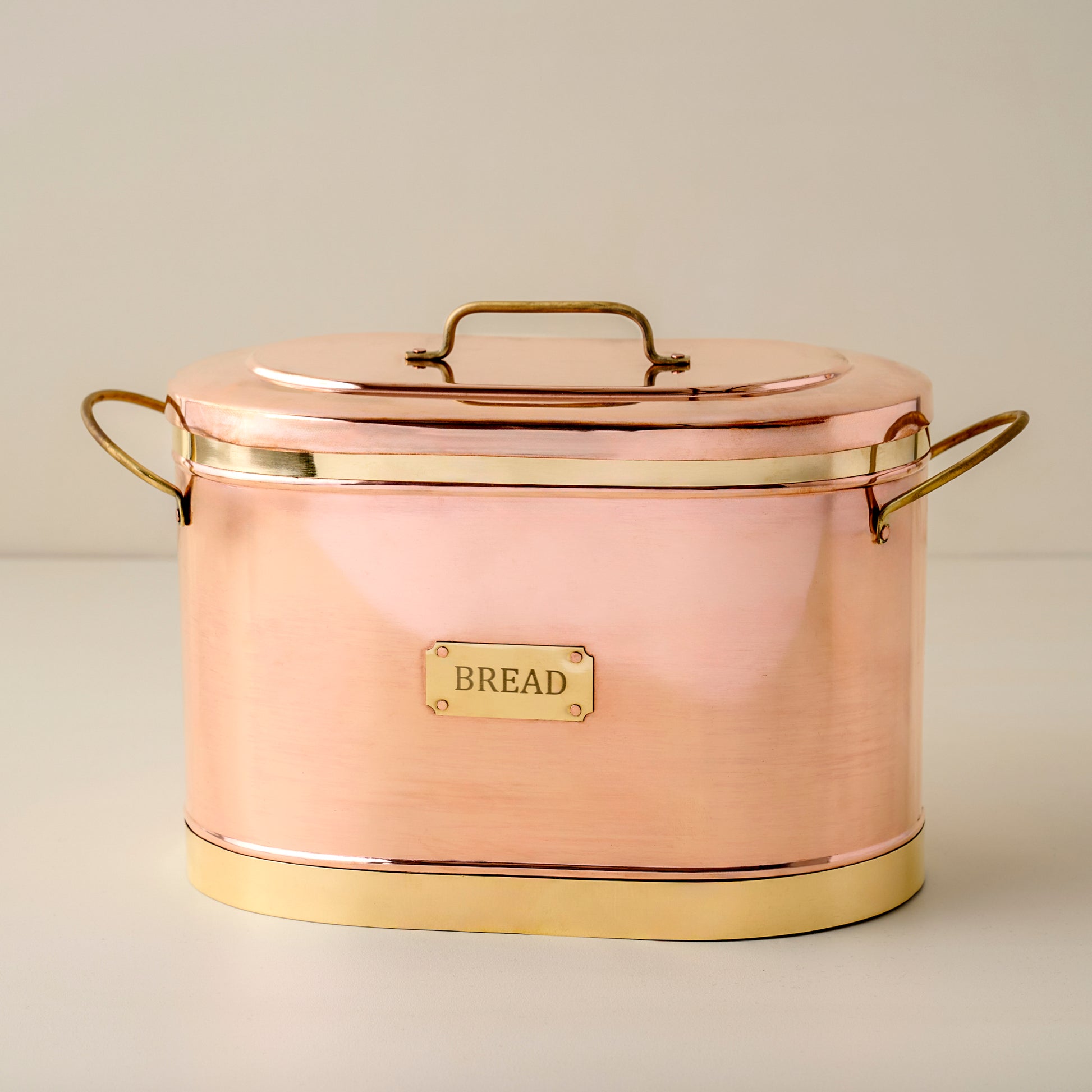 Copper bread bin with gold accents on a light background