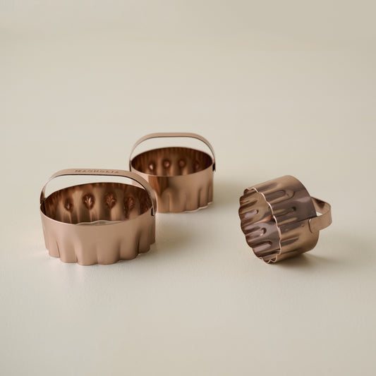 Three copper biscuit cutters on a beige background