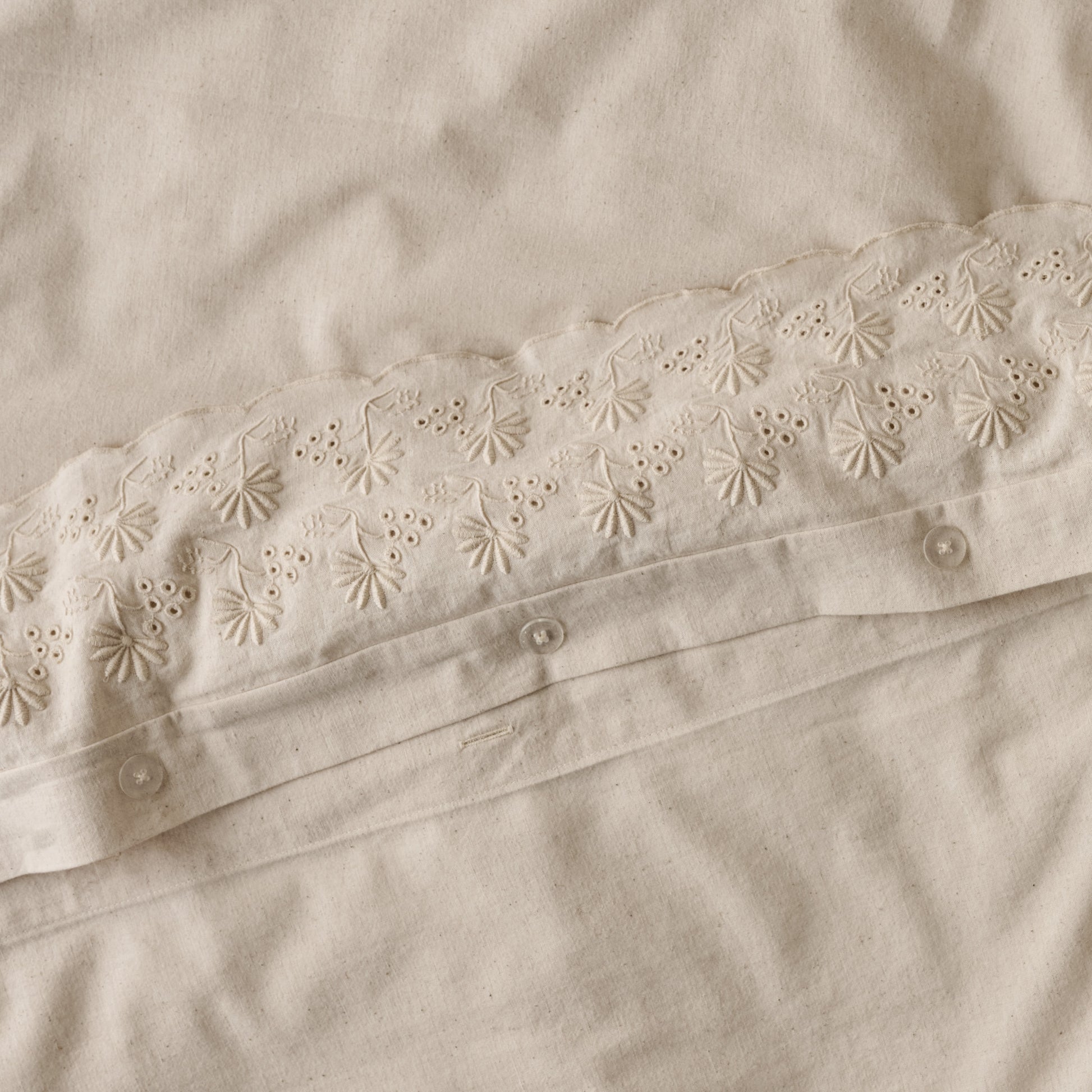 Clara Eyelet Flange Duvet Cover in color Natural button closures up close