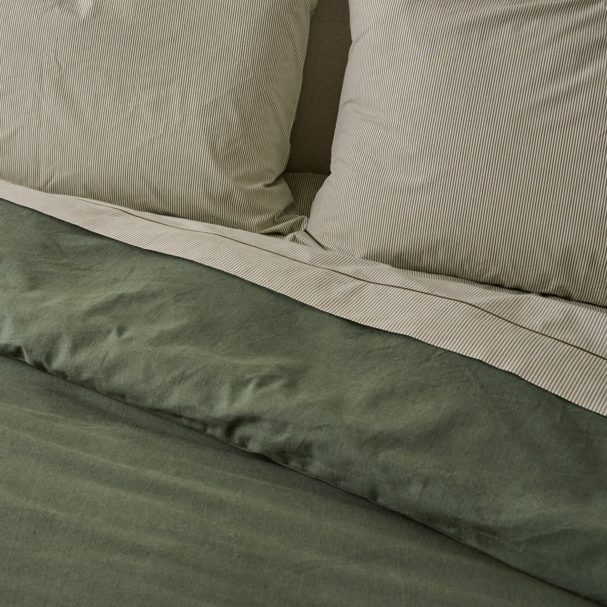 Clara Eyelet Flange Duvet Cover in color Olive Night shown on bed with pinstripe sheets