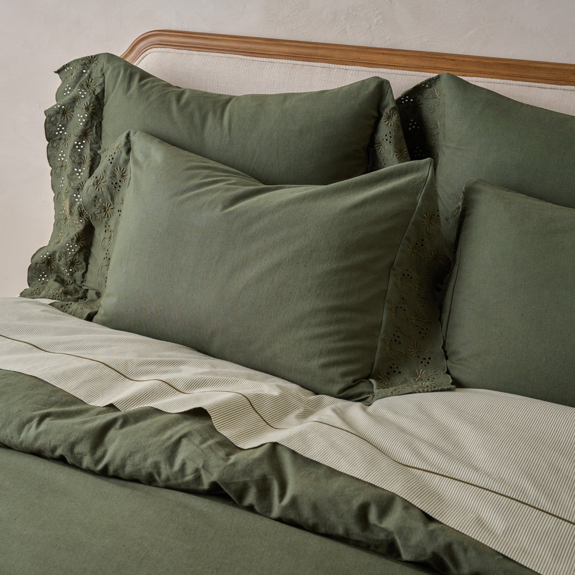 Clara Eyelet Flange Shams in Olive NIght shown on bed