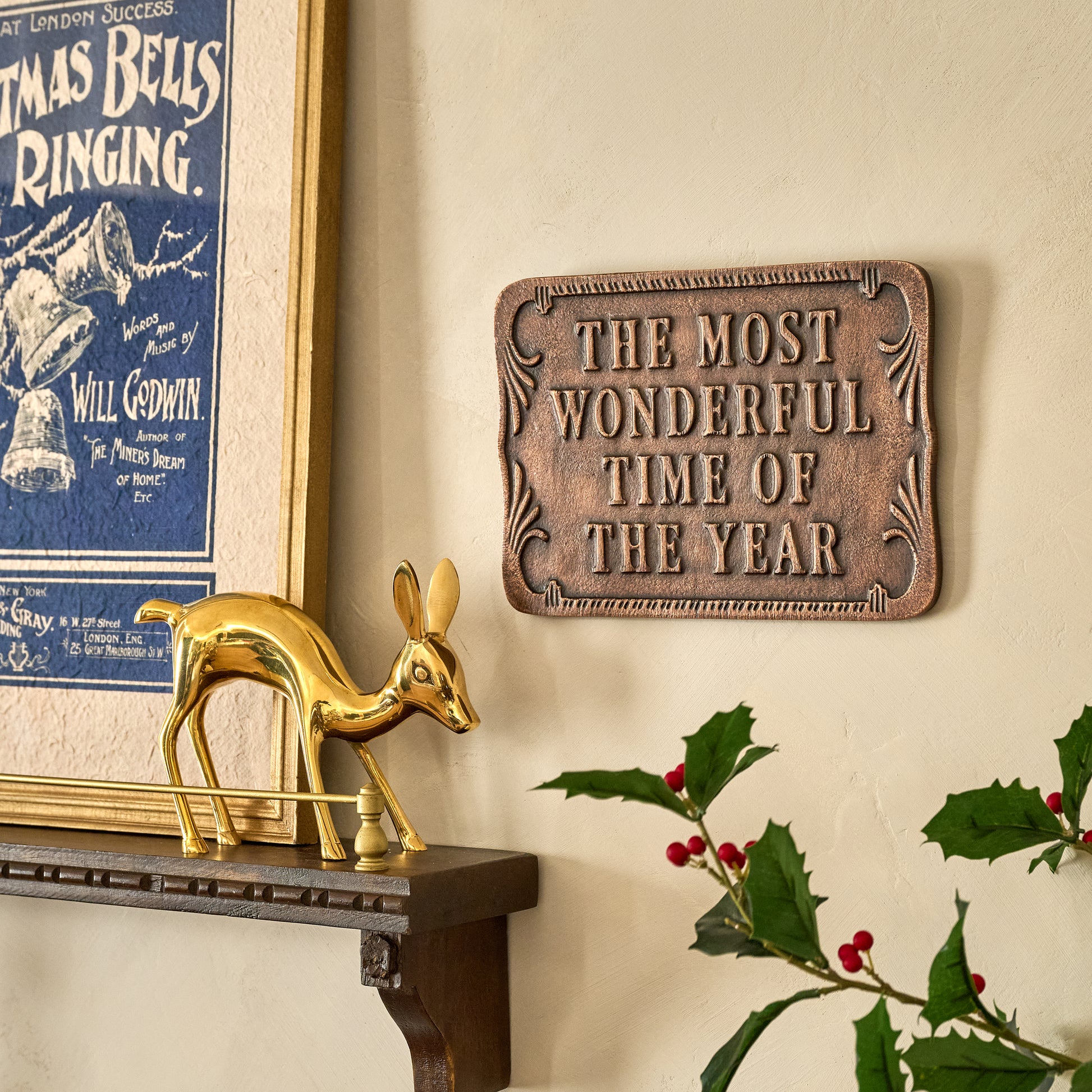 The Most Wonderful Time of the Year Metal Wall Plaque shown hung on wall by wall shelf