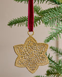 Ornate Brass Star Ornament shown hung from tree branch