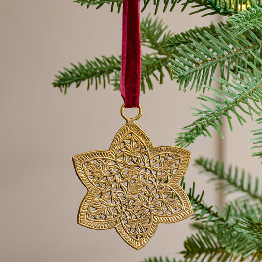 Ornate Brass Star Ornament shown hung from tree branch
