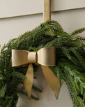 Clara Brass Bow Wreath Hanger shown holding wreath