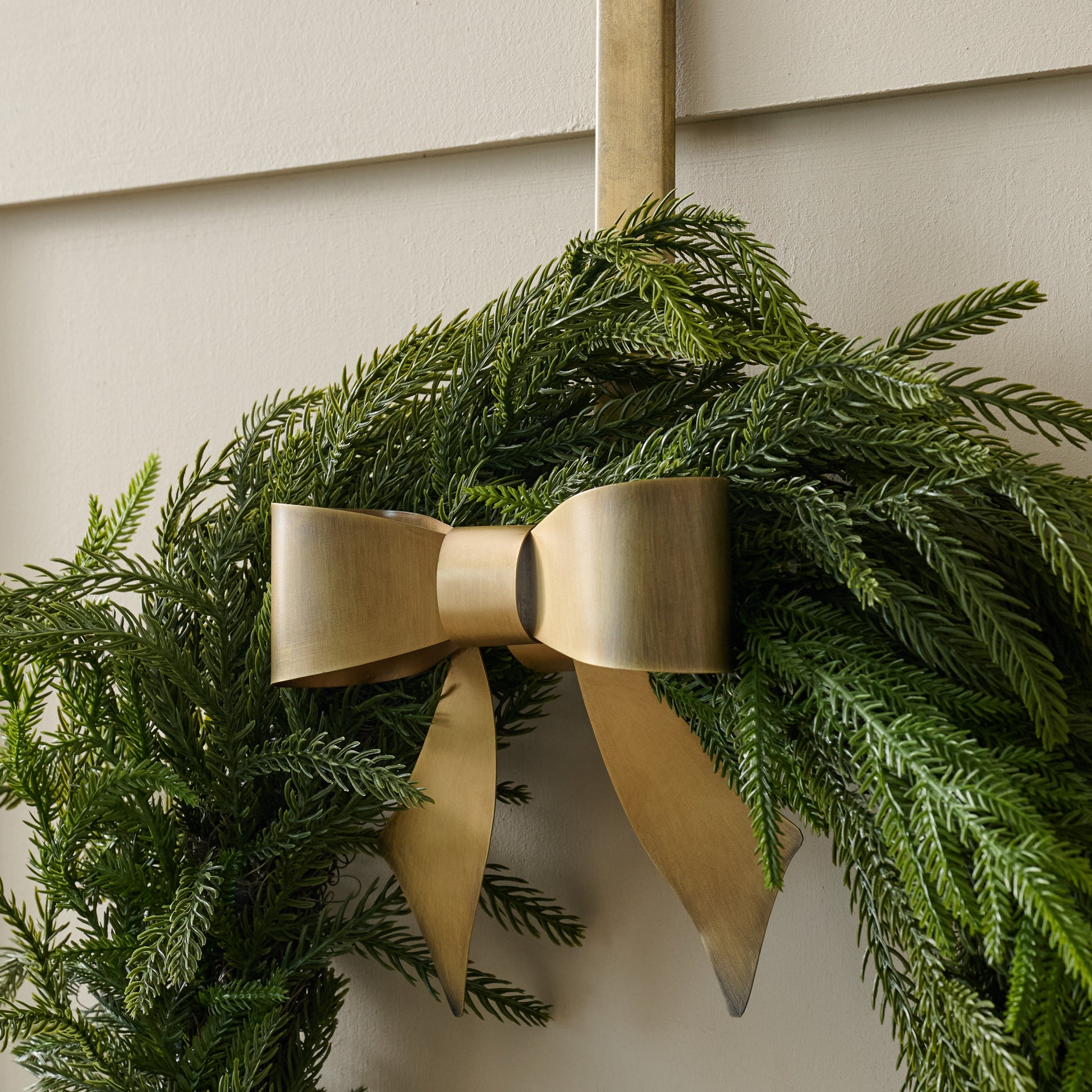 Clara Brass Bow Wreath Hanger shown holding wreath