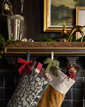Eleanor Carved Wood Stocking Holder shown holding stockings on mantel
