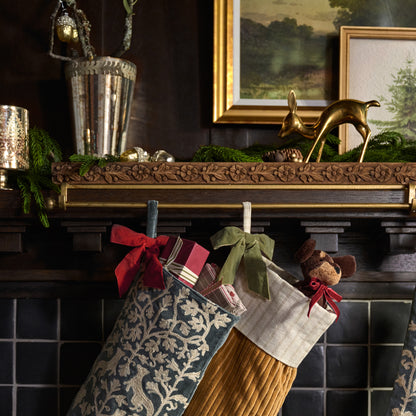 Eleanor Carved Wood Stocking Holder shown holding stockings on mantel