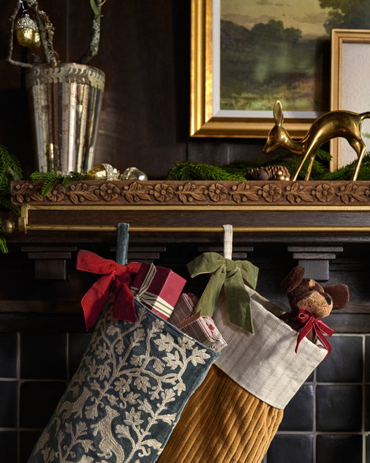 Eleanor Carved Wood Stocking Holder shown holding stockings on mantel