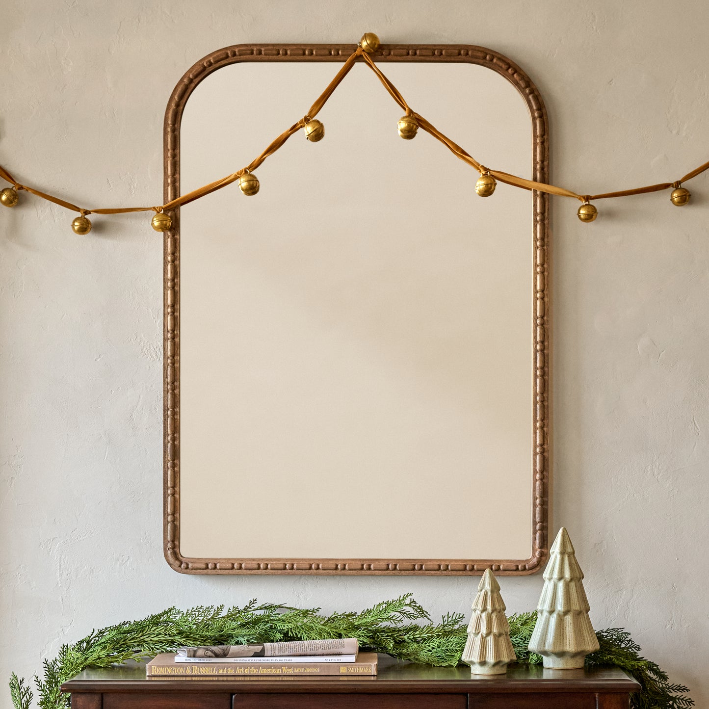 Nicolette Arched Wood Mirror shown hung above console table with holiday decor
