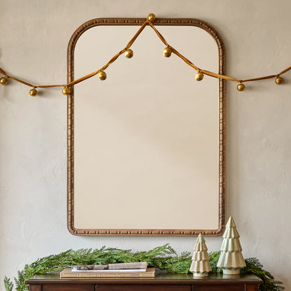 Nicolette Arched Wood Mirror shown hung above console table with holiday decor