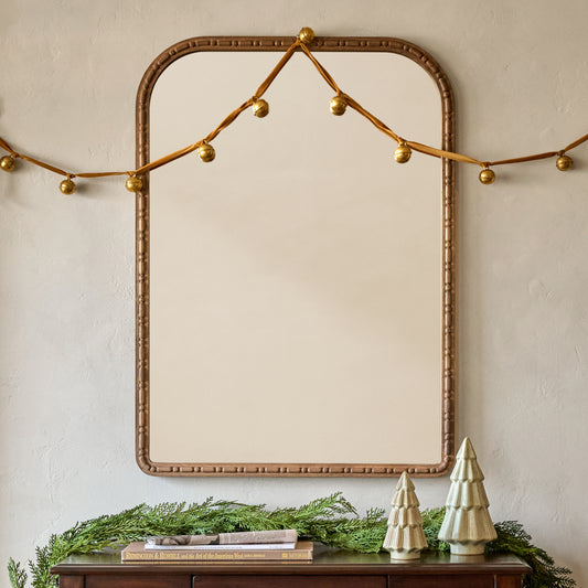 Nicolette Arched Wood Mirror shown hung above console table with holiday decor