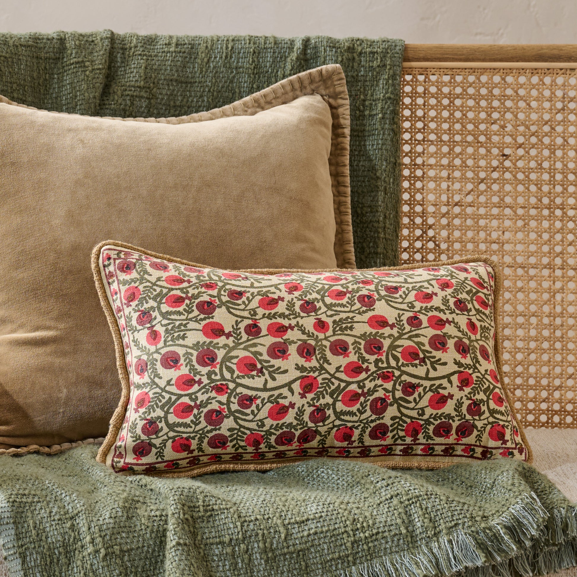 Festive Pomegranate Block Print Small Lumbar Pillow shown on bench with another throw pillow and throw blanket