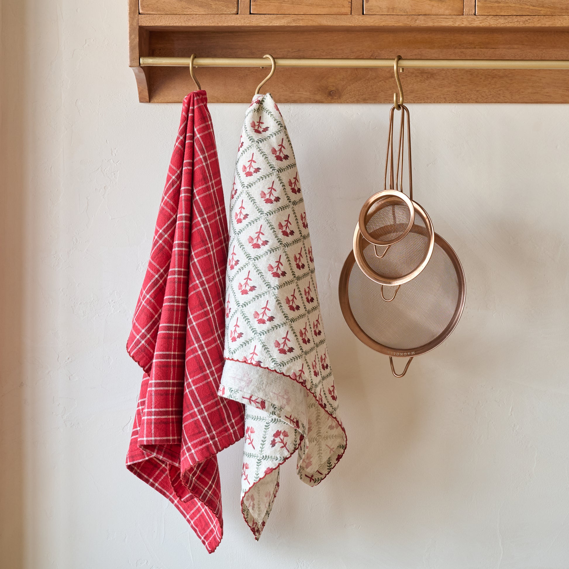 Magnolia Vintage Red Plaid Tea Towel shown hung with other tea towel and kitchen utensils