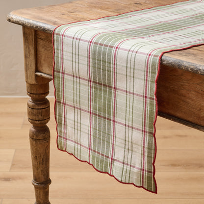Magnolia Festive Plaid Reversible Table Runner shown on table with green plaid side facing up