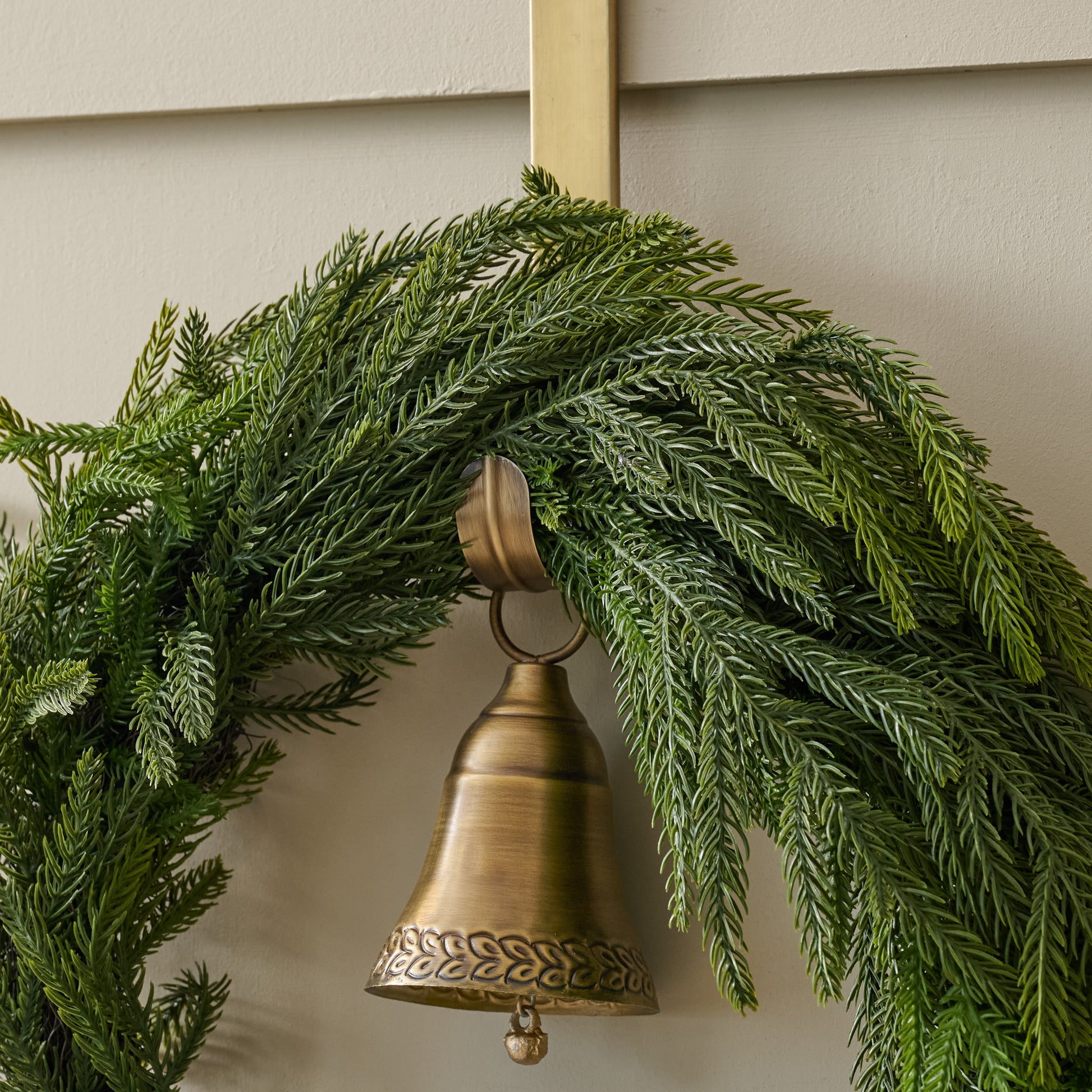 Gabriel Brass Bell Wreath Hanger up close shown holding wreath