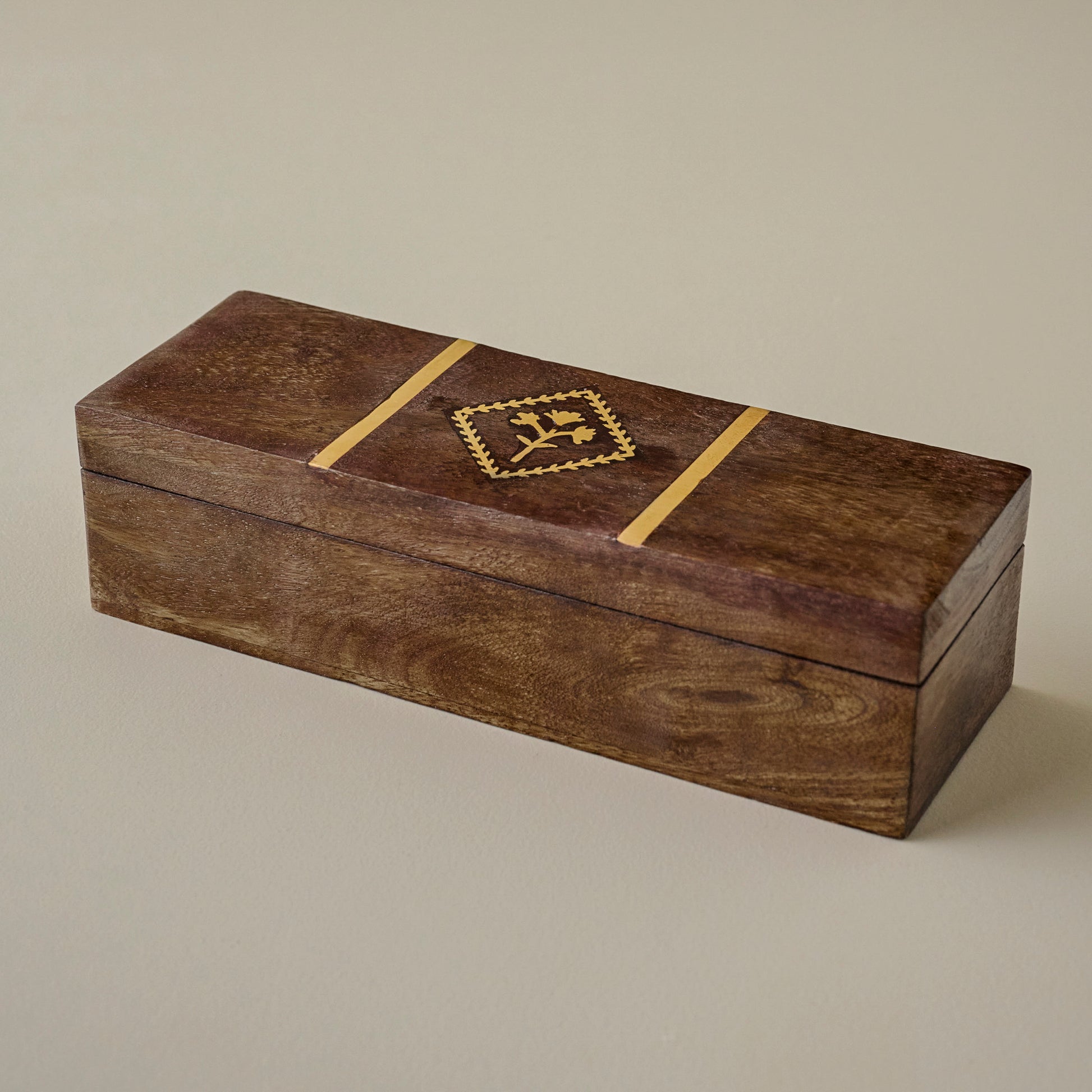 Wooden box with a decorative brass tulip emblem on a beige background